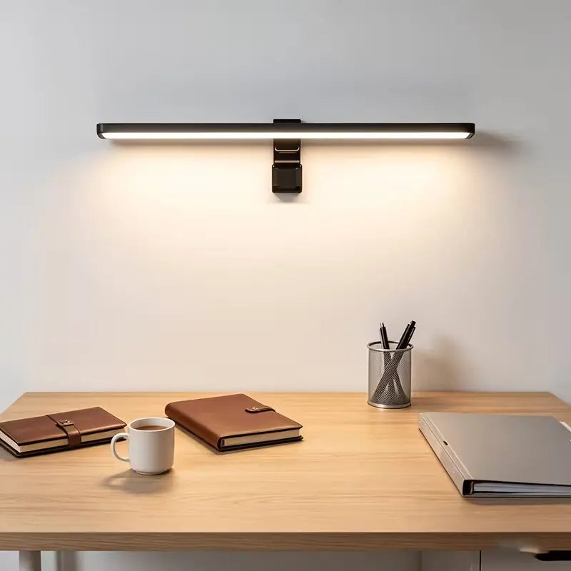 A modern light bar monitor light is mounted above a wooden desk, illuminating the workspace.