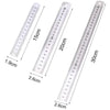 A stainless steel double-sided precision ruler showing various measurements in centimeters and inches.