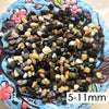 A close-up view of various decorative stone pebbles in mixed shades of black, gray, and tan on a blue ceramic surface.