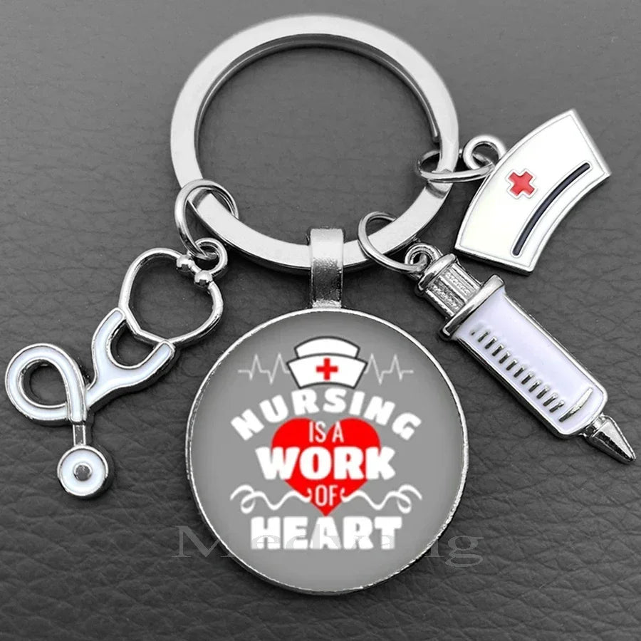 Silver nurse keychain featuring a glass dome pendant with the text Nursing is a work of heart