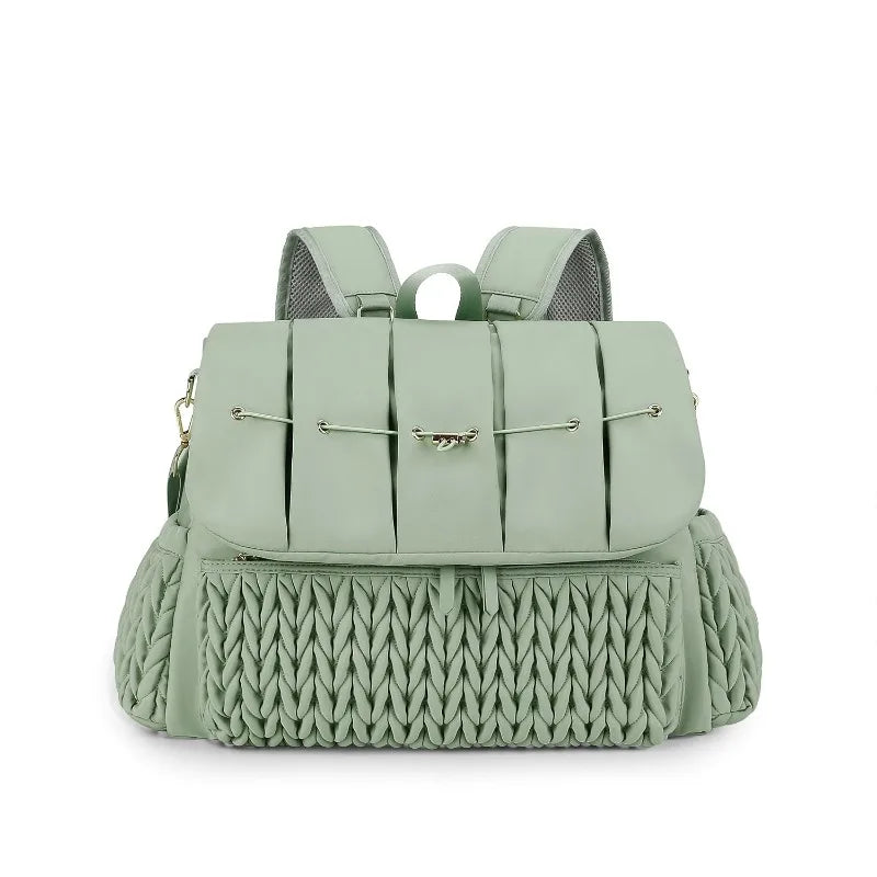 A light sage green waterproof diaper bag with mesh straps and a textured knit bottom.