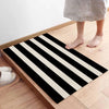 A black and white striped non-slip door mat placed on a wooden floor.