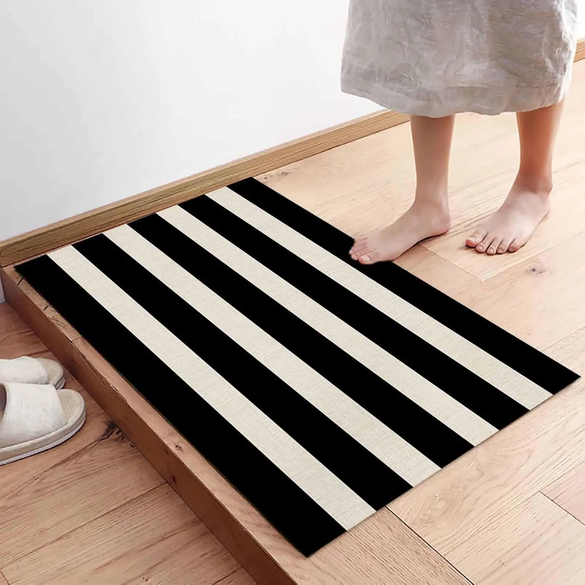 A black and white striped non-slip door mat placed on a wooden floor.