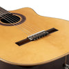 A close-up view of a light brown classical guitar with a silver-plated nylon string set installed.
