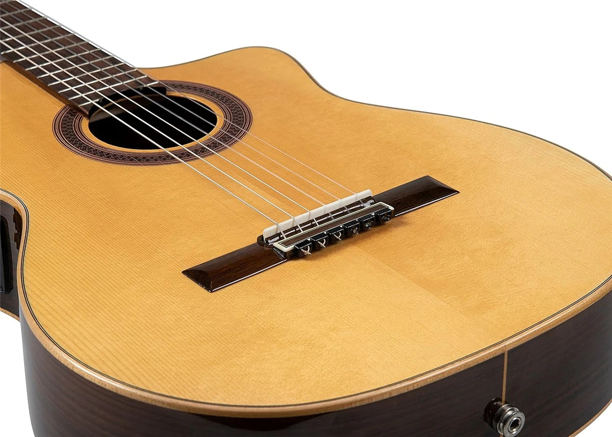 A close-up view of a light brown classical guitar with a silver-plated nylon string set installed.