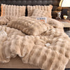 A beige faux fur bedding set featuring a duvet and pillows on a bed.