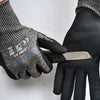 A hand wearing black cut-resistant work gloves holding a silver utility knife.