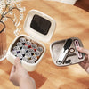 A hand opens a compact magnetic sewing kit containing 20 needles and various thread colors on a wooden table.