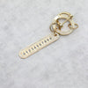Gold-toned key fob cover with a numbered bar and circular ring, featuring small pave diamonds.