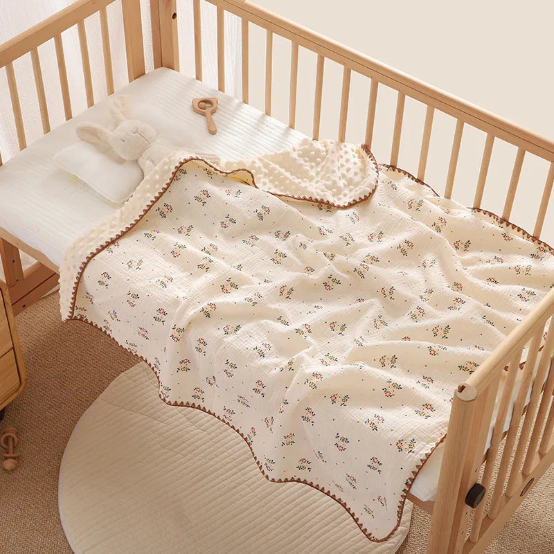 A beige cotton gauze baby swaddle blanket with a bear print is displayed in a wooden crib.