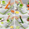 A hand is using a green and gray multifunctional vegetable cutter to slice carrots, celery, and cucumbers.