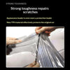 Hands are applying a clear tint film to a car's headlight or taillight to repair scratches.