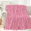 A pink leopard print flannel throw blanket draped over a light-colored sofa.
