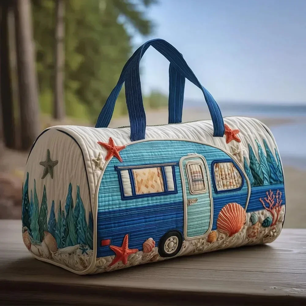 A quilted blue and white travel duffle bag with starfish and nature stitching sitting on a wooden surface.