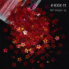 A pile of red and gold holographic star sequins scattered on a black surface.