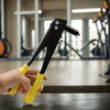 A hand holds a black heavy-duty pop rivet gun kit with yellow handles on a dark surface.