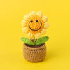 Handcrafted crochet sunflower with a yellow face growing in a brown pot.