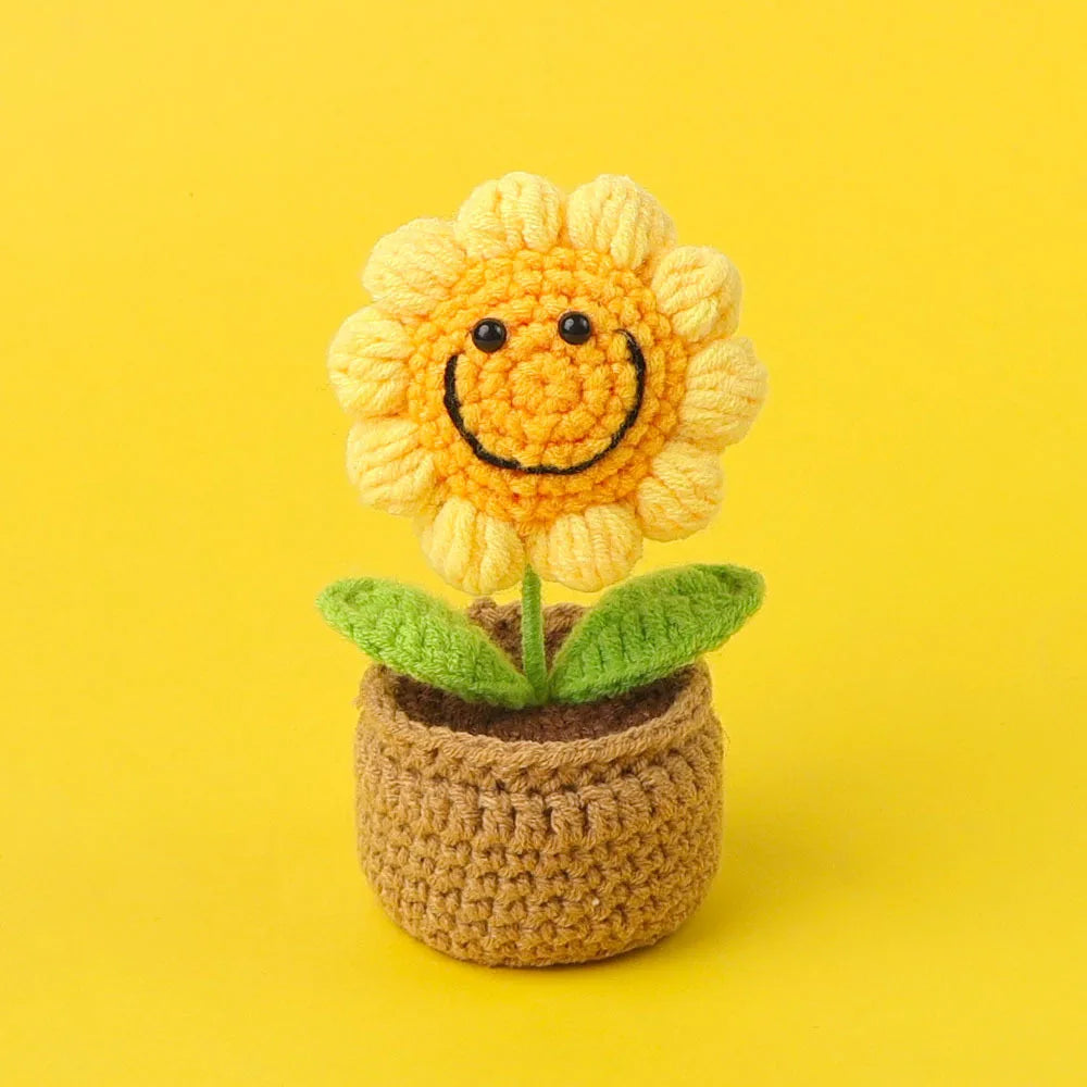 Handcrafted crochet sunflower with a yellow face growing in a brown pot.