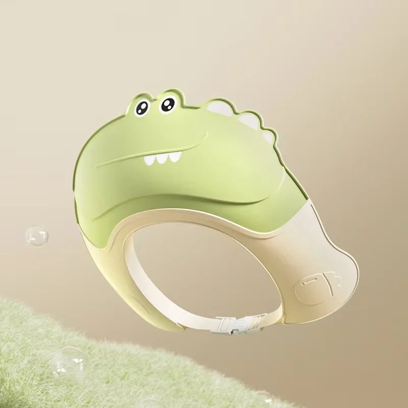 A light green adjustable baby bath shampoo shield cap with ear protection shown against a blurred green background.