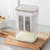 A clear plastic yogurt strainer with a fine mesh filter is placed on a wooden cutting board.