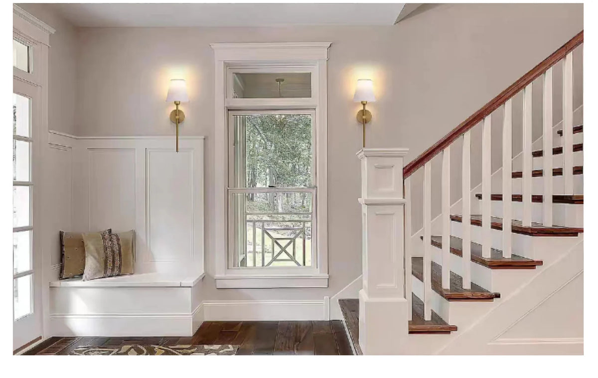 A hallway features a white built-in shelf with a window and two wall sconces illuminating the area.