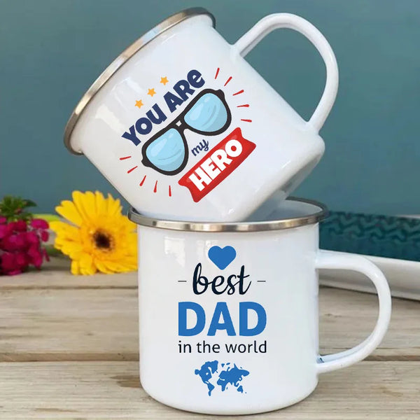 A white enamel mug featuring graphics that read You Are my Hero and Best Dad in the world