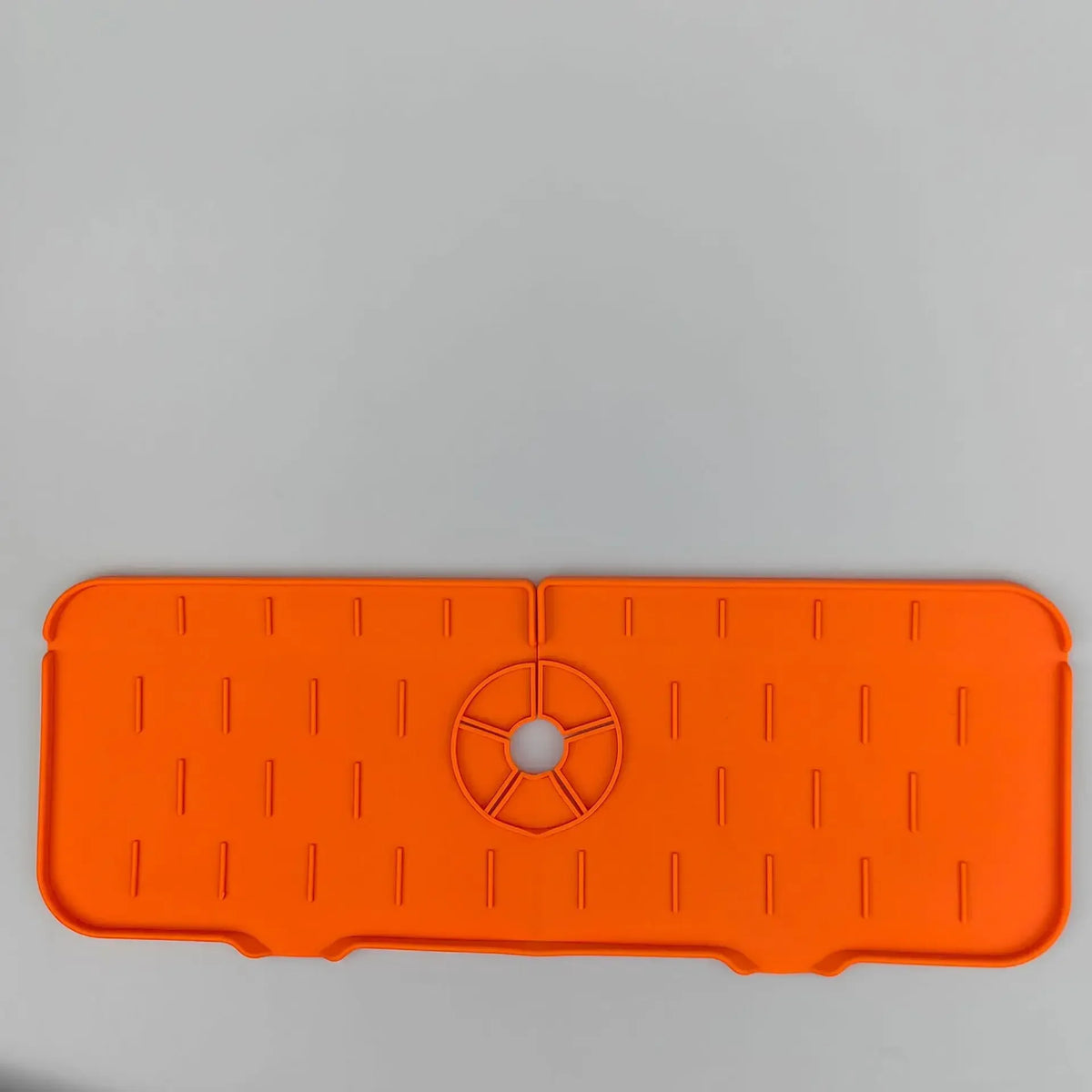 Orange silicone kitchen sink mat with raised ridges and a central drain hole