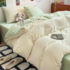 A bed with a light green duvet cover set featuring cream and pale green pillows and bedding.