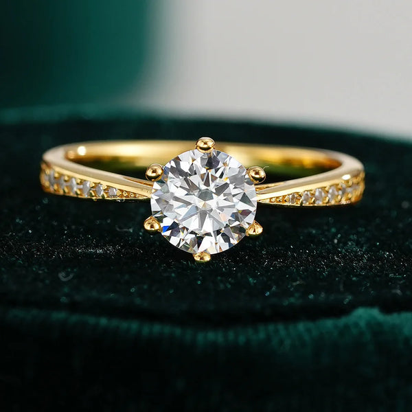 Nahaufnahme eines geometrischen Moissanit-Rings in goldbeschichtetem Sterling-Silber auf dunkelgrünem Samt.