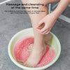 A person is using a pink suction cup foot massage mat to cleanse and massage their feet in a bowl.