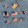 A collection of enamel pins featuring American flag designs, including a gold eagle pin, USA emblem, and patriotic cross shap
