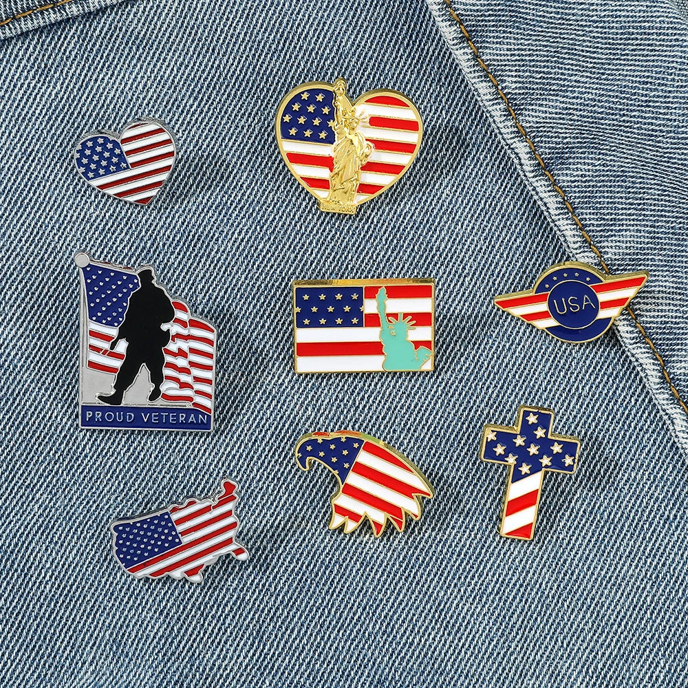 A collection of enamel pins featuring American flag designs, including a gold eagle pin, USA emblem, and patriotic cross shap