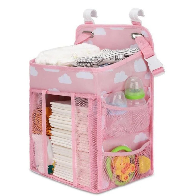 A pink hanging diaper storage organizer with multiple compartments for storing diapers and baby items.