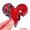 A red heart shaped patch embroidered with various colored pins and needles on a black fabric background.
