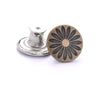 A round, dark bronze button with a flower pattern next to a silver button repair kit base.