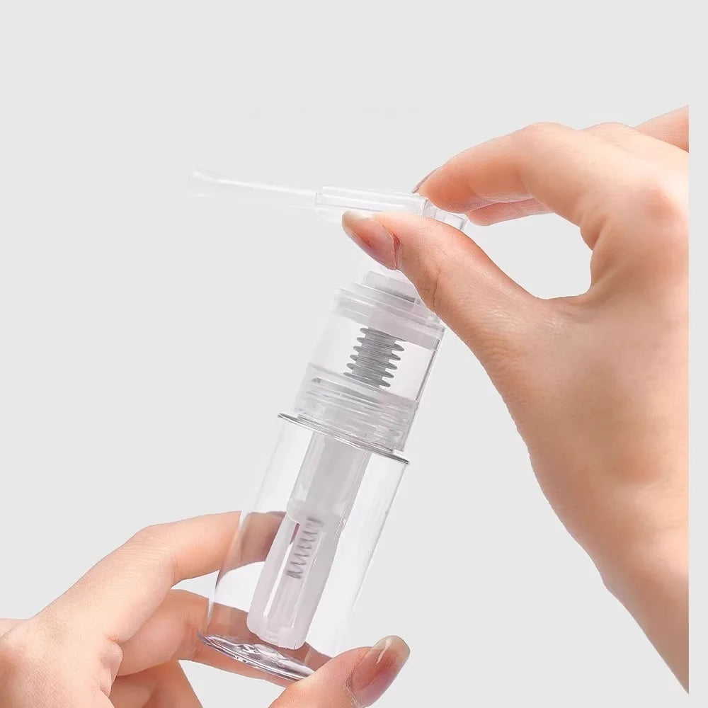 A hand is holding a clear glass spray bottle with a fine mist nozzle, demonstrating the refillable design.