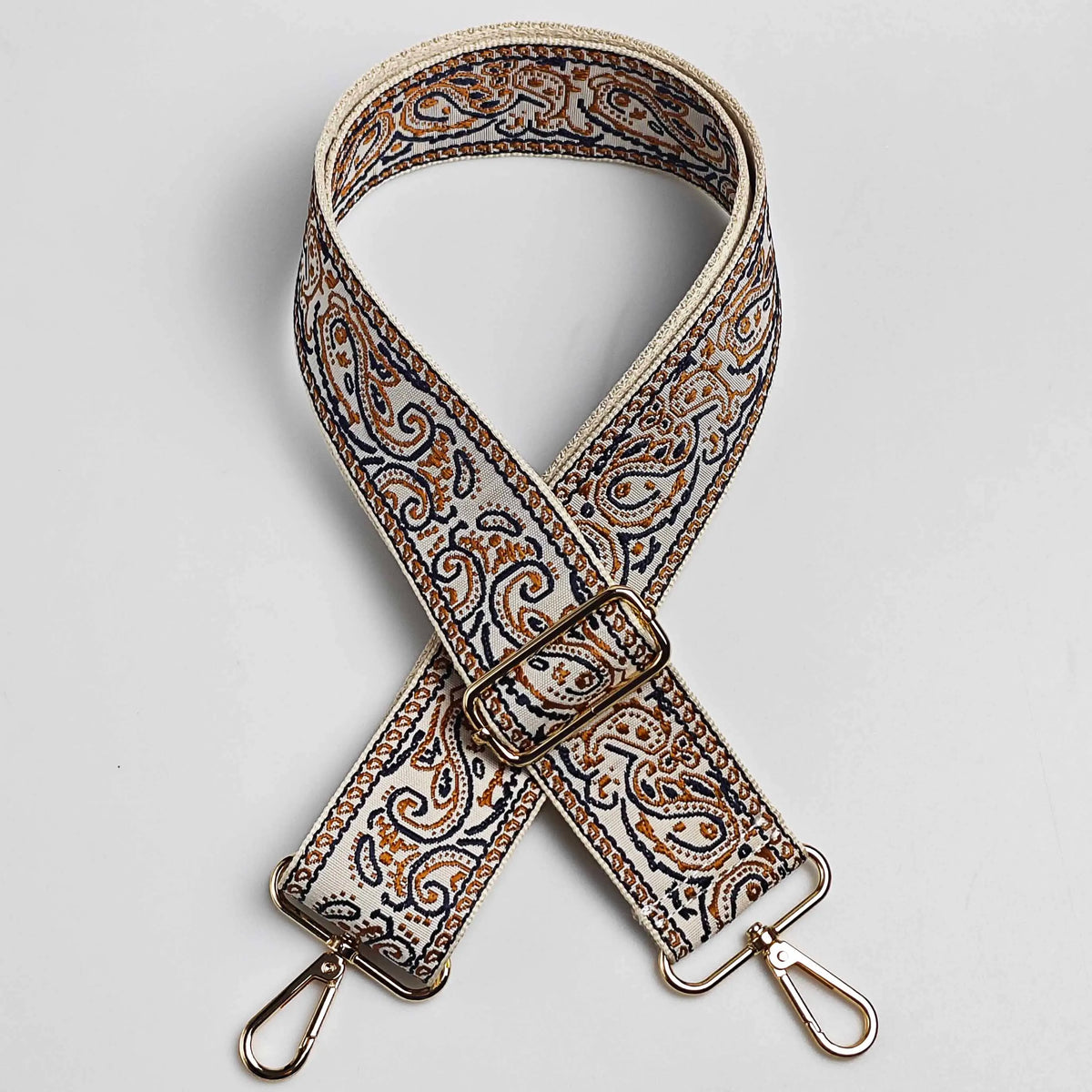 A beige and brown paisley jacquard strap with a gold-toned buckle and metal hardware.