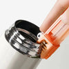A hand is holding a stainless steel and silicone multi-purpose cleaning brush set designed for bottles, cups, and straws.