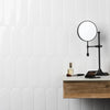 A close-up of a modern bathroom wall featuring white raised tile paneling and a black wall-mounted magnifying mirror.