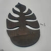 A dark brown wooden wall-mounted storage rack shaped like a tropical leaf for plant decor.