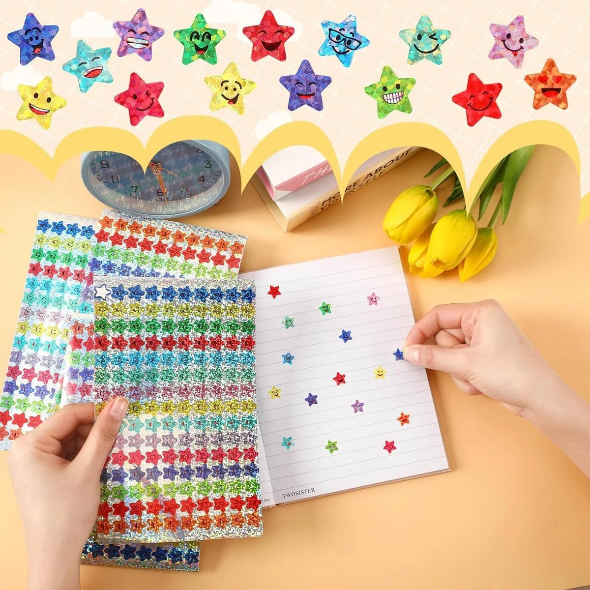 A hand is holding a sheet of glitter star stickers and a piece of lined paper with star designs on a light background.