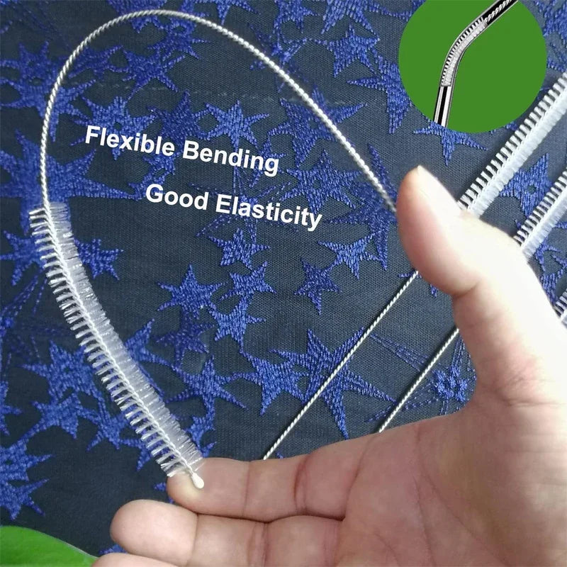 A hand holds a flexible bending cleaning brush set with stainless steel handles against a dark blue patterned fabric.