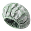 A large, satin-lined waterproof shower cap for hair protection with a green and white leaf pattern.