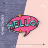 Pink embroidered lettering patch shaped like a speech bubble with the word HELLO in teal and pink thread