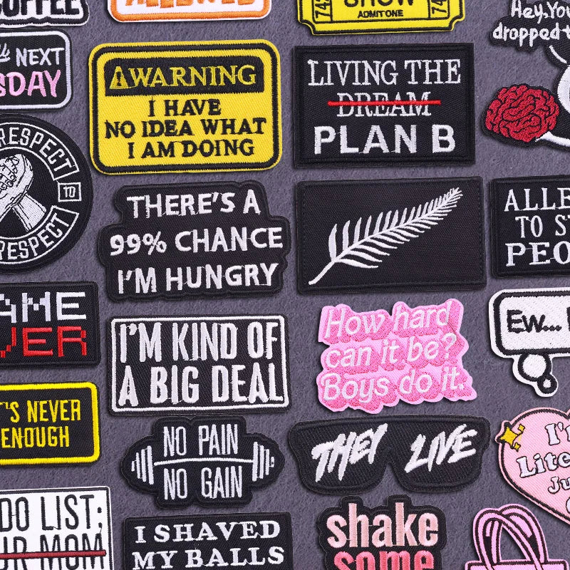 A collection of black, yellow, and pink embroidered iron-on letter and word patches with various phrases like WARNING LIVING 