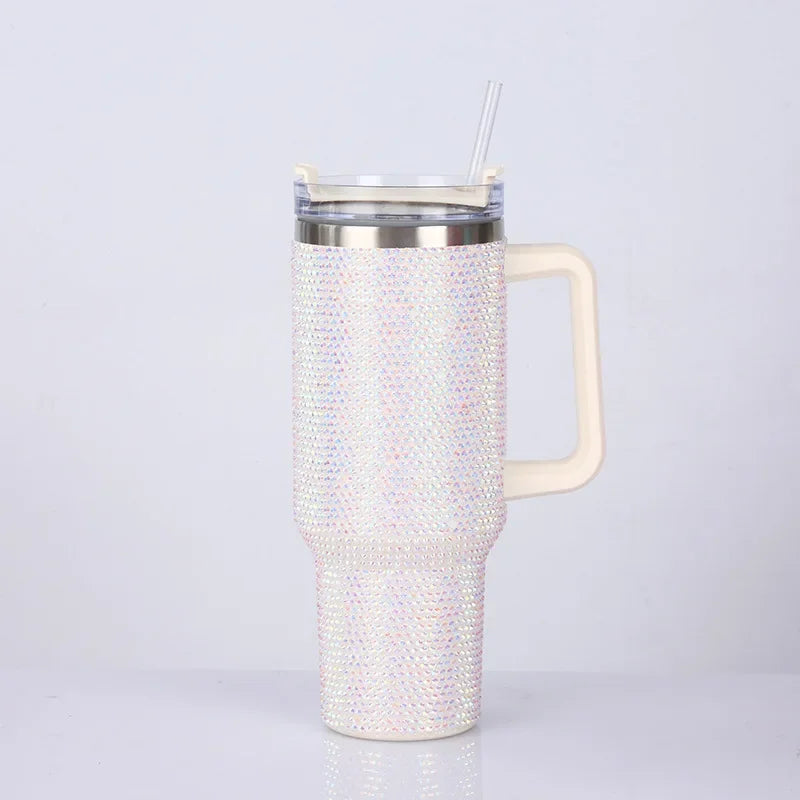 A clear tumbler with a silver lid and straw, featuring a sparkly iridescent rhinestone pattern on the body.