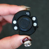 A hand holds a black fidget spinner with white accents and a silver ring.