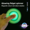 A hand is interacting with a glowing green fidget spinner, demonstrating its silent rotation.