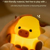 A hand holds a yellow silicone cow night light illuminating the face and body.