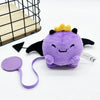 A cute purple plush doll with yellow crown and black wings resting on a white surface.